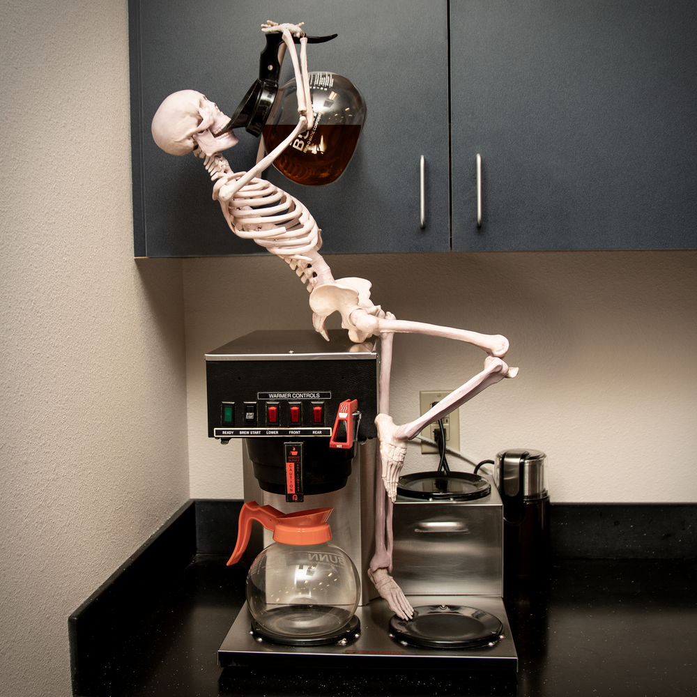 Skeleton drinking coffee on a coffee machine